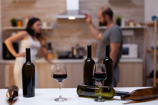 Close up of bottles and glasses filled with wine, liquor, booze and alcoholic beverage for alcohol addicts in background chatting. Intoxicated drunk people with unhealthy addiction