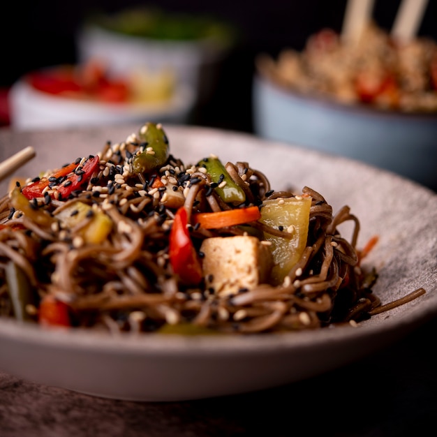 Close-up of bowl of noodles with sesame seeds and vegetables