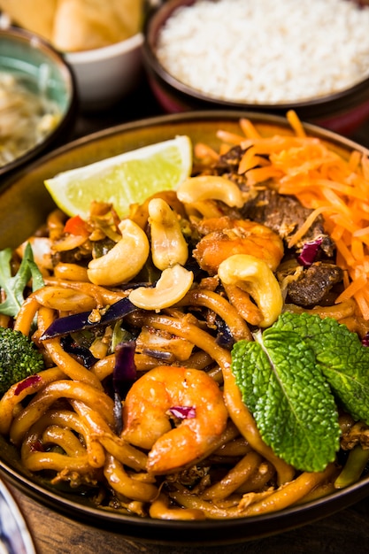 Free photo close-up bowl of udon noodles with nuts; lemon slice; mint and beefs