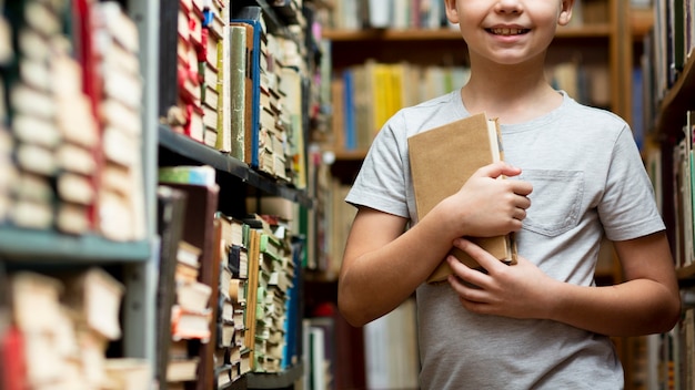 Foto gratuita ragazzo del primo piano fra gli scaffali per libri