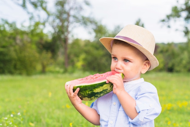 Close-up of boy eating watermelon standing in the park