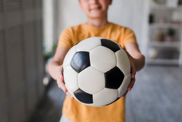 Close-up of boy giving soccer ball toward camera