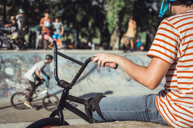 Foto gratuita primo piano della maniglia della bicicletta della tenuta della mano del ragazzo al parco