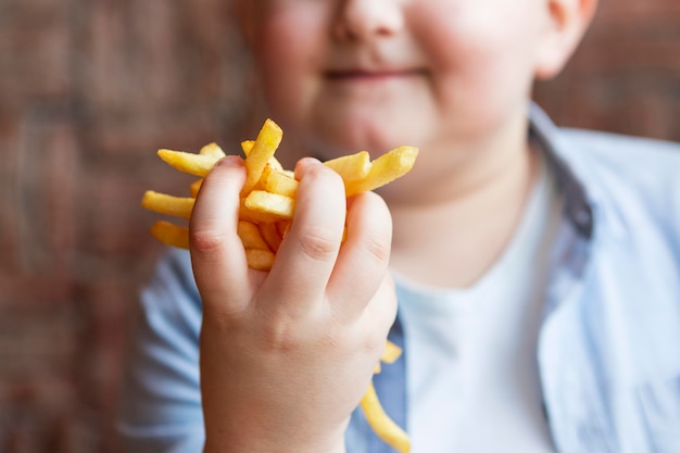 フライドポテトを持っている少年をクローズアップ