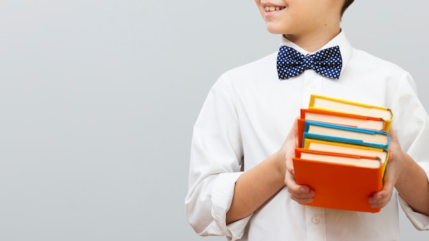 Close-up boy holding stack of books