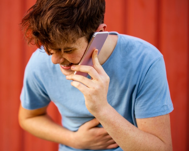 Foto gratuita ragazzo del primo piano che ride sul telefono