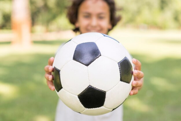 Мальчик крупным планом играет с футбольным мячом