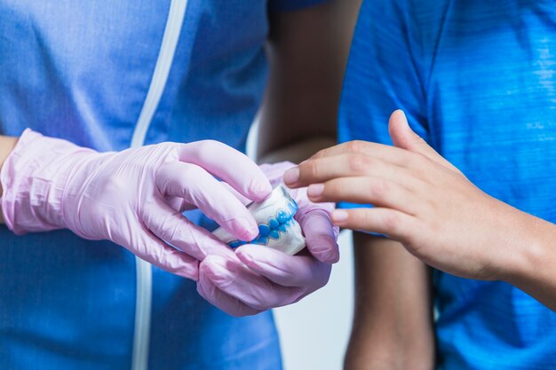 Close-up of a boy's hand touching teeth plaster mold hold by dentist