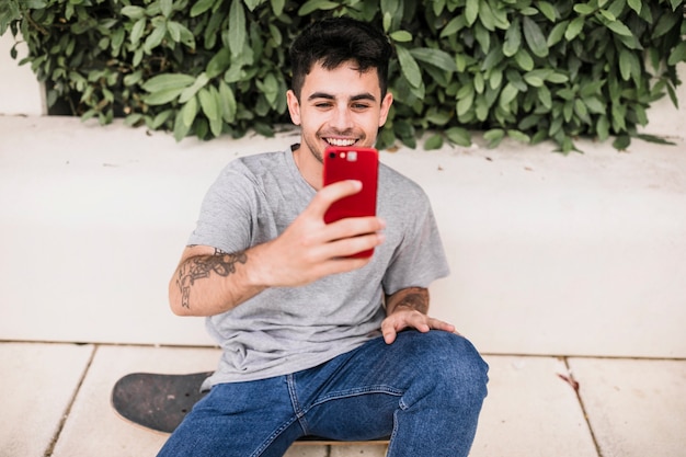 그의 빨간 휴대폰 selfie을 복용하는 소년의 근접 촬영
