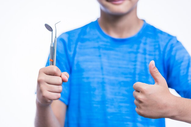 Крупный план мальчик с зубоврачебными инструментами gesturing палец вверх