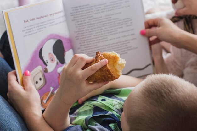 Close-up of boy with sweet and book background