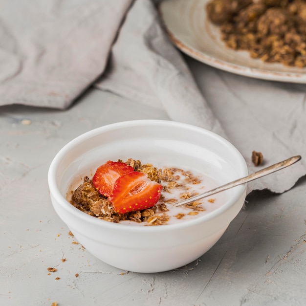 Foto gratuita ciotola della prima colazione del primo piano con granola e la fragola