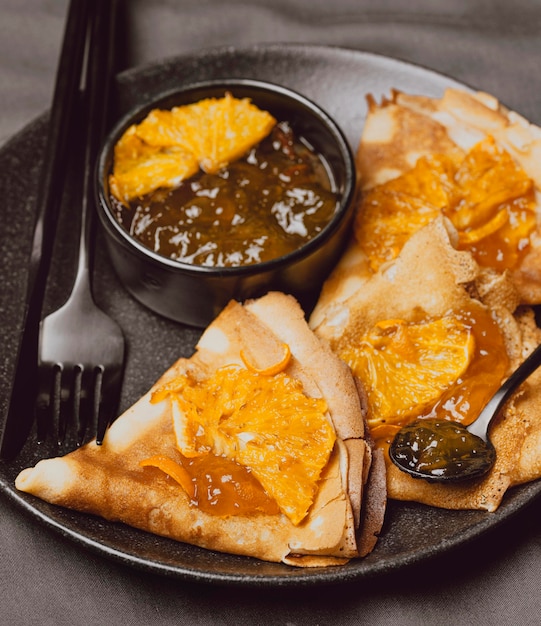 Close-up of breakfast crepes on bed with jam