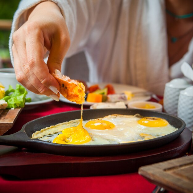 Close-up breakfast on a table with a red tablecloth fried eggs, cheese cheese, cucumbers, tomatoes, lettuce, coffee