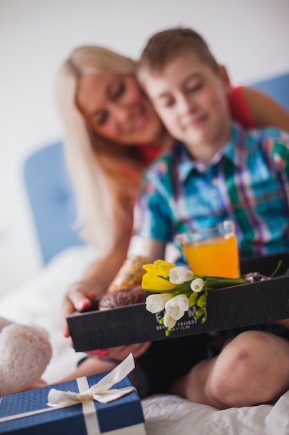 Close-up of breakfast tray with blurred mother and son