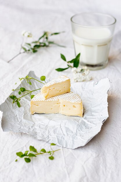 Крупным планом сыр бри со стаканом молока