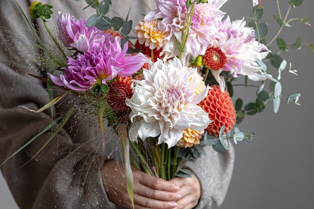 女性の手に菊と明るいお祝いの花束のクローズアップ。