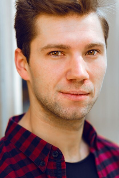 Close up bright portrait of young handsome hipster man, wearing plaid shirt, pretty face, brown eyes.