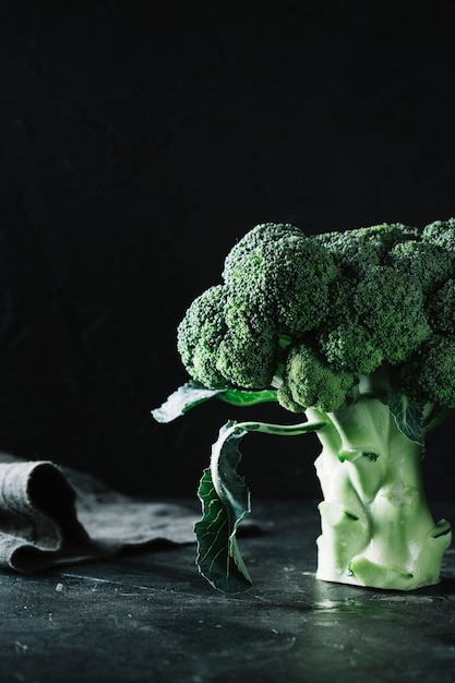 Foto gratuita broccoli del primo piano su fondo e sul panno neri