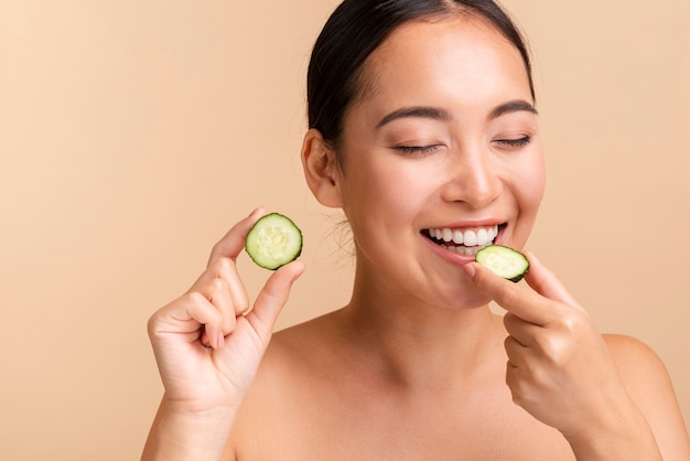 Close-up brunette woman biting cucumber slice