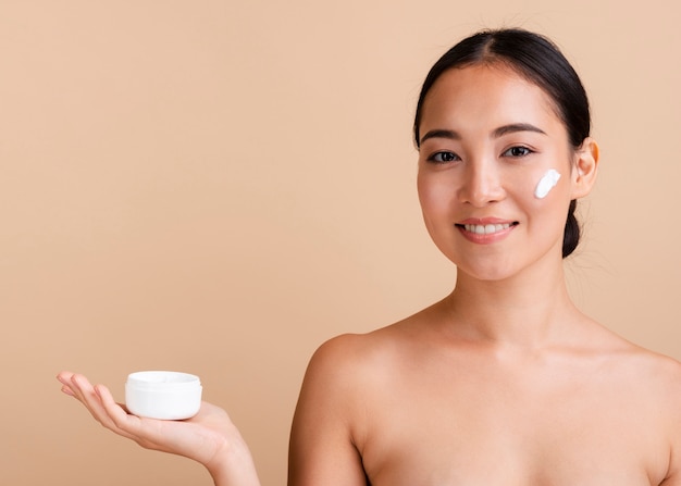 Close-up brunette woman with face cream 