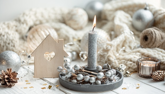 Close up of burning candle on blurred background of Christmas decor details.