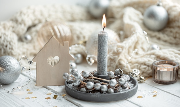 Close up of burning candle on blurred background of Christmas decor details.