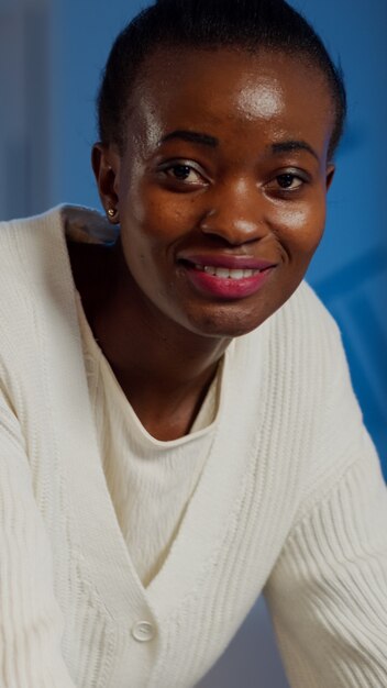 Close up of business african woman smiling at camera after typing on laptop