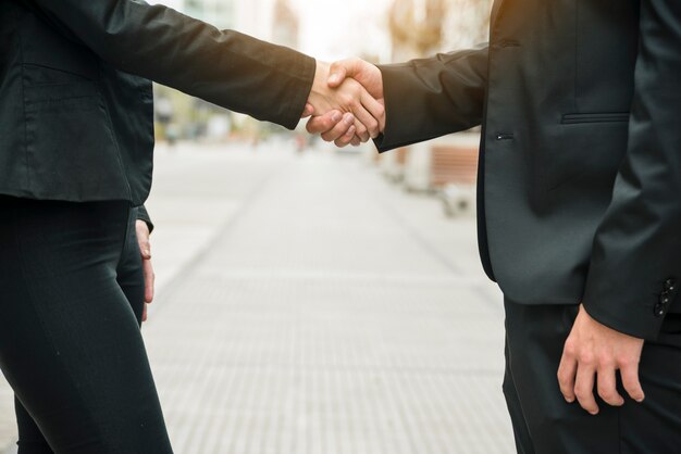 Close-up of business people standing on street shaking each other's hand