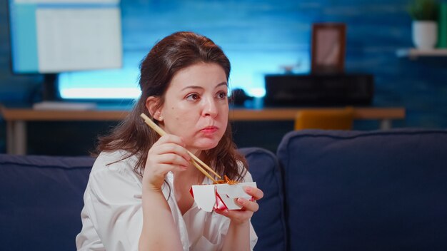 Close up of business woman eating asian food at tv