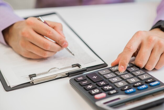 Крупный план бизнесмена Расчет счетов-фактур с помощью калькулятора