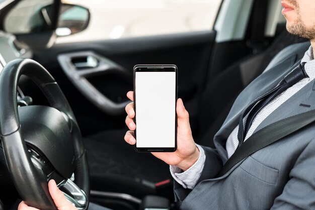 Close-up of a businessman driving car showing mobile phone with white display screen