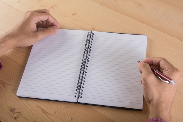 Close up of businessman hand writing with notebook in table. Business working concept.