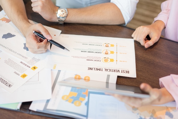 Close-up of businessman reading reports and discussing them with female colleague.