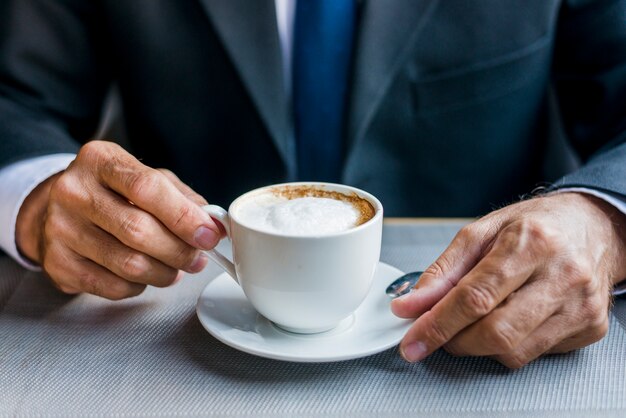 Close-up of a businessman's hand holding cup of coffee