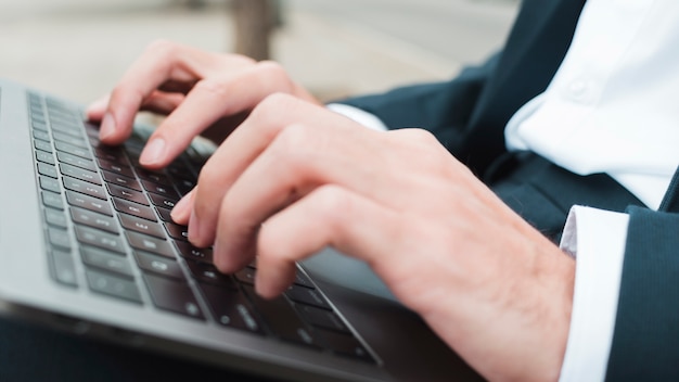 Free photo close-up of businessman's hand typing on laptop