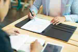 Free photo close-up of businessman sitting at table and filling in document