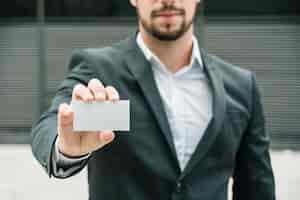 Free photo close-up of a businessman standing at outdoors showing blank white business card