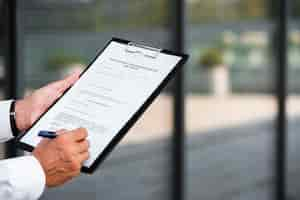 Free photo close-up businessman writing on clipboard