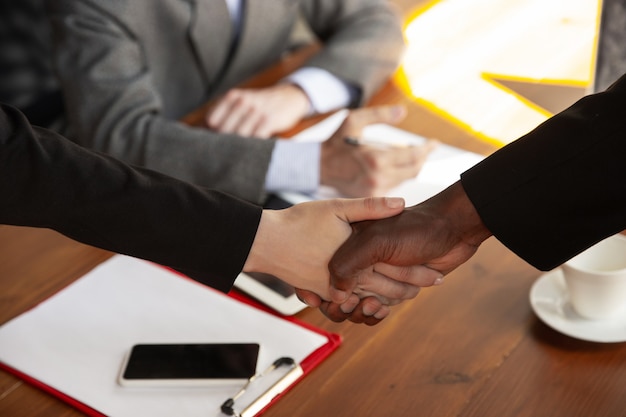 Close up of businessmen shaking hands in conference room