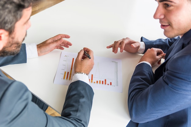 Free photo close-up of businessmen working on company financial report over the white desk