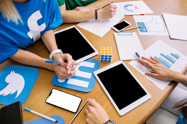 Close-up of businesspeople with digital tablet and social media icons on table