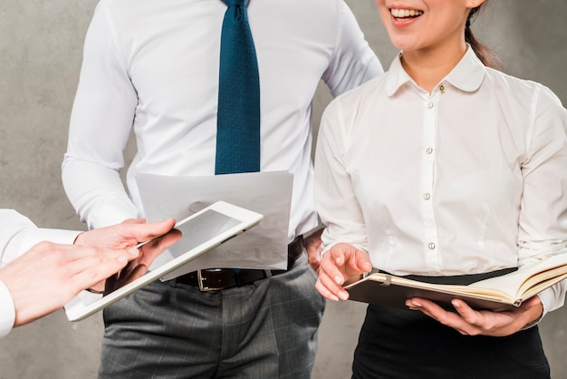 Close-up of businesspeople working together against grey wall