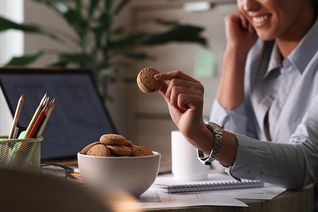 Primo piano di una donna d'affari che mangia i biscotti durante una pausa nel suo ufficio