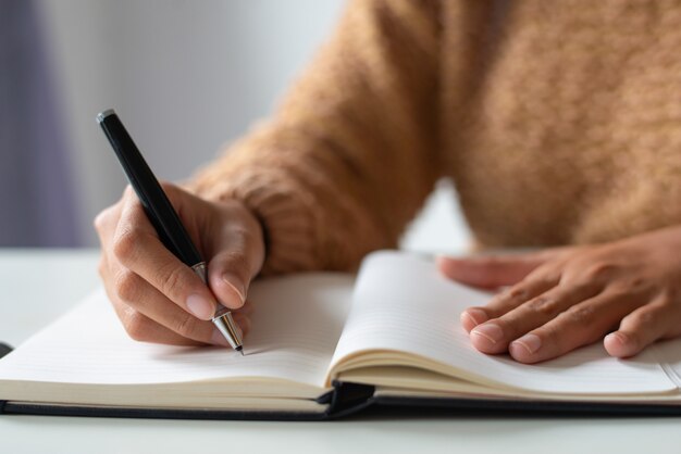 Close-up of businesswoman making notes in personal organizer