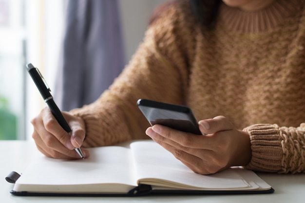 Close-up of businesswoman planning timetable using smartphone