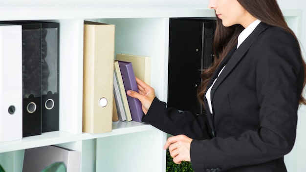 Free photo close-up of a businesswoman removing book from shelf