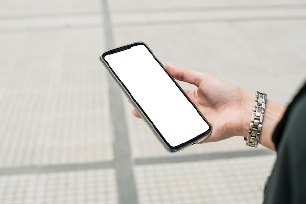 Close-up of businesswoman's hand holding smartphone displaying white screen