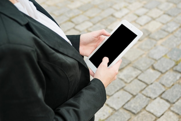 Foto gratuita primo piano della mano di una donna d'affari utilizzando il telefono cellulare vuoto all'aperto