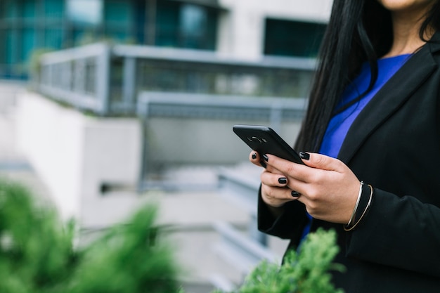 Foto gratuita primo piano della mano di una donna d'affari utilizzando il cellulare